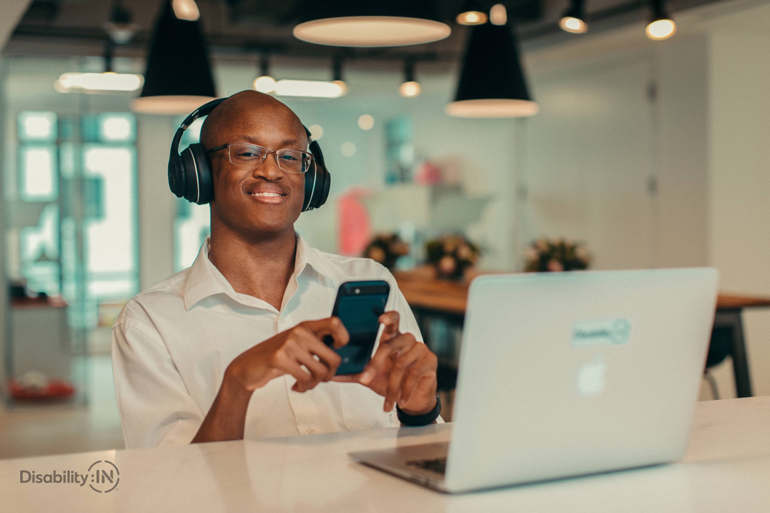 Young man wearing headphones sits at a laptop in cafe