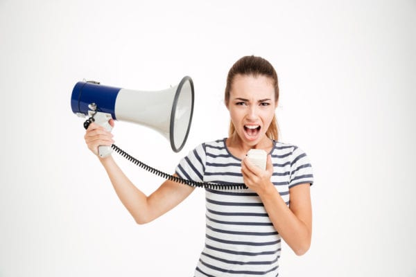 Young woman shouting into loudspeaker at yourself