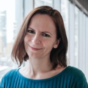 Kate Kalcevich, a white woman with brown hair wearing a blue collarless shirt.