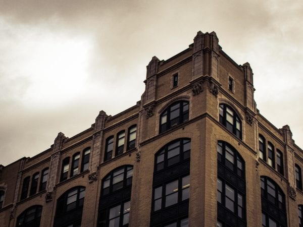 A big brick building with dark windows against an overcast sky