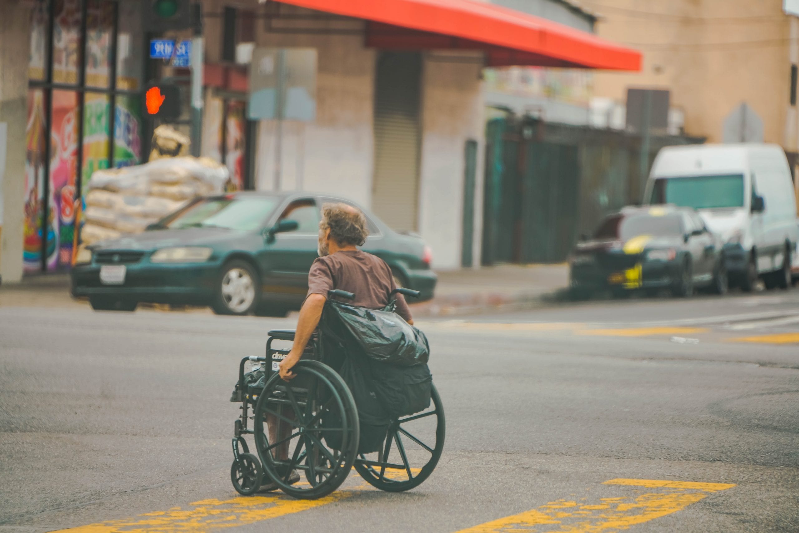 A man crossing the street in a wheelchair on a grey day