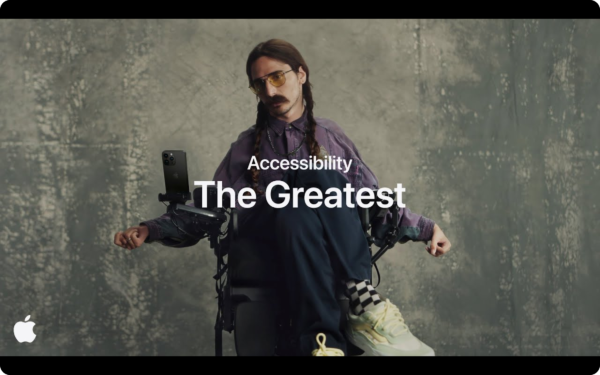 The cover image for Apple’s commercial “Accessibility - The Greatest”. The image features a man wearing glasses in a powered wheelchair looking down at his iphone that is held by a phone holder that’s attached to his wheelchair