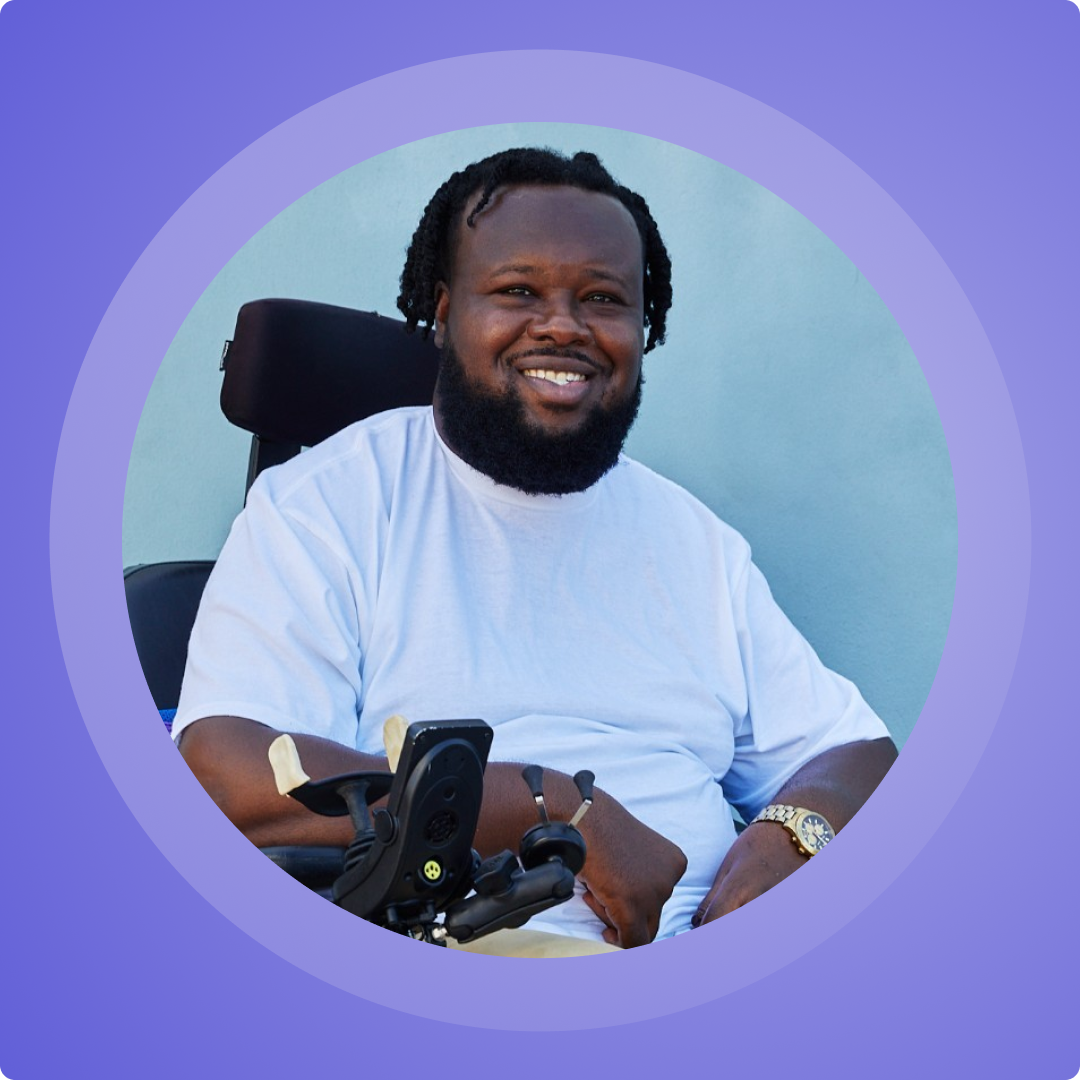 Headshot of Rhonel Cinous in a purple frame. Rhonel is a Black man with short twists, smiling in a power wheelchair.