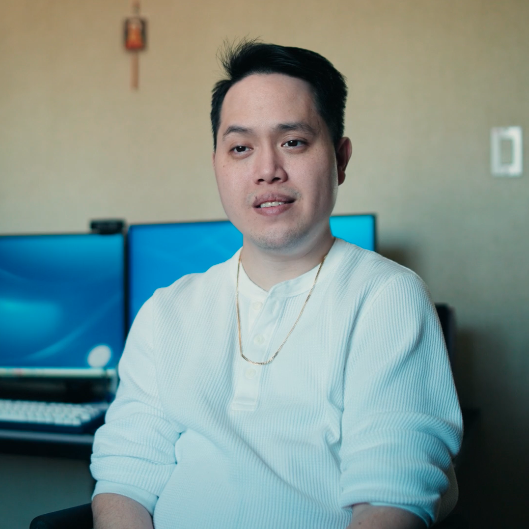 tin-n Tin, an asian man with short dark hair seated with two computer monitors in the background
