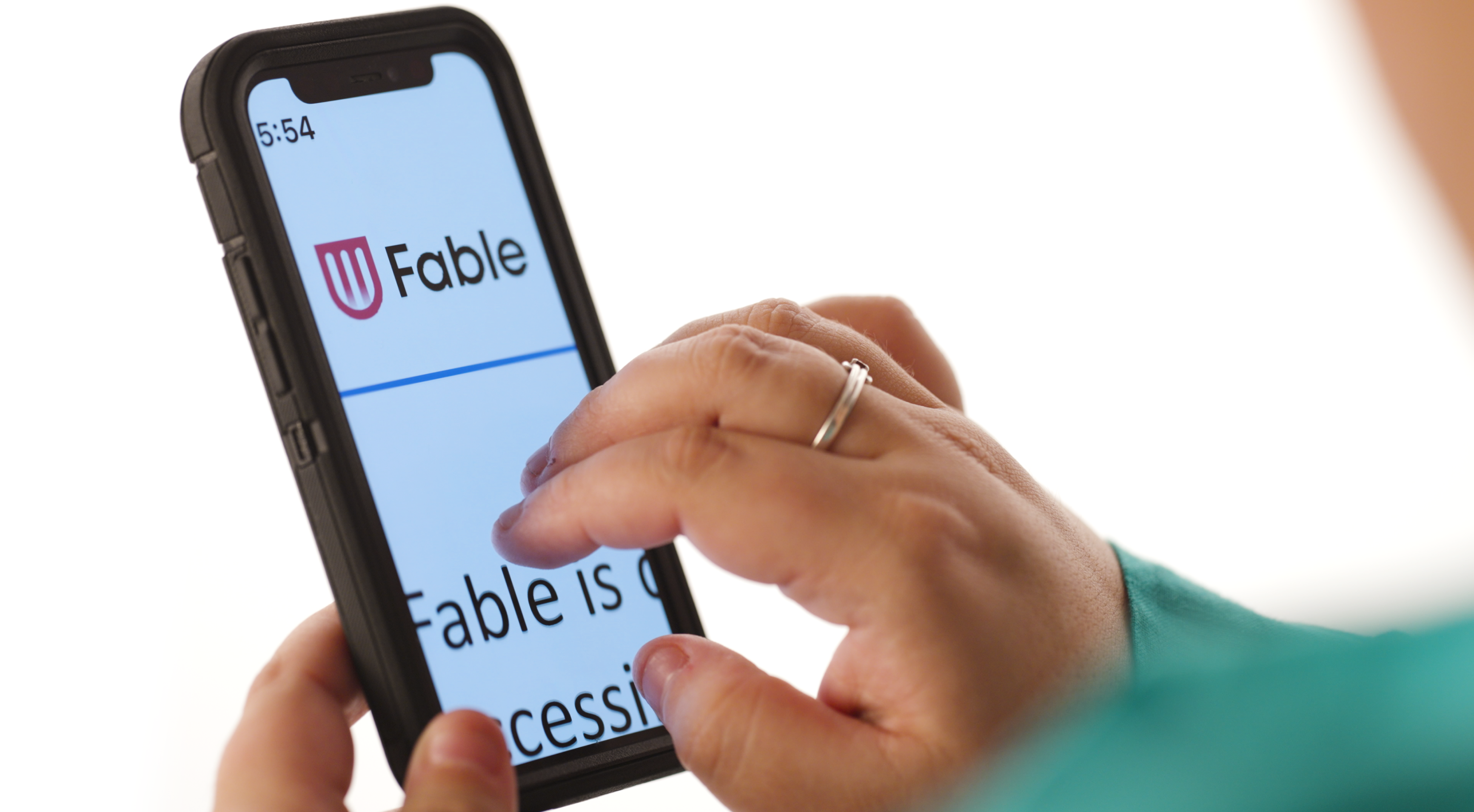 A close up shot of a woman's hand navigating a smartphone with her thumb, pointer and middle fingers. The screen is displaying a magnified version of the Fable website