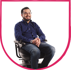 Fable Community member headshot 2 Man seated in a powered wheelchair, smiling with hands clasped